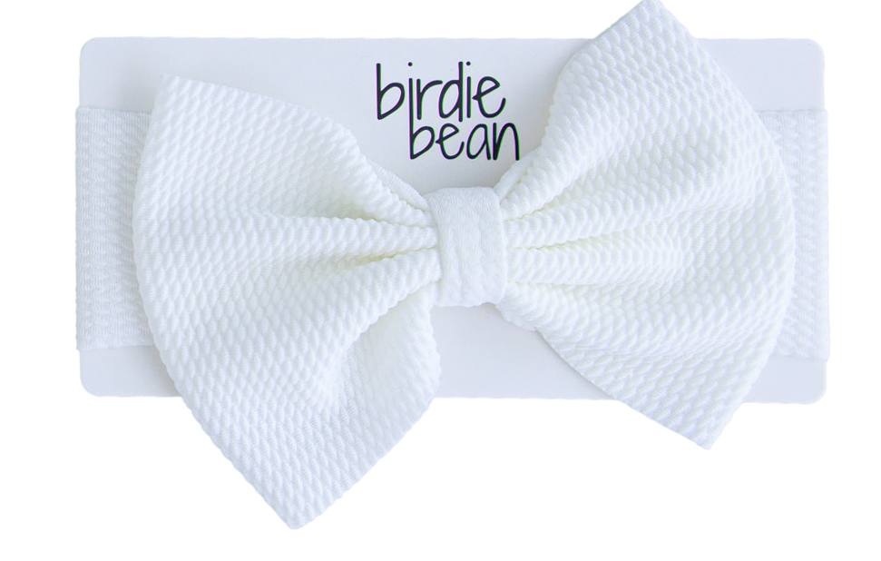 White textured bow headband with 'birdie bean' branding on a white background